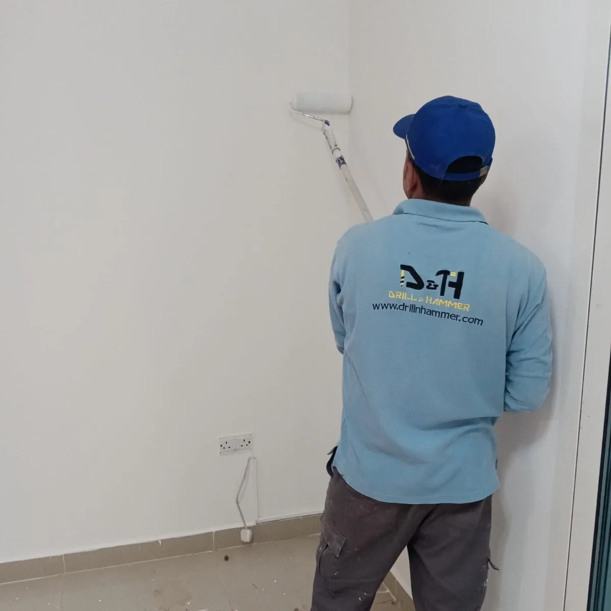 a professional expert is painting a wall by drill and hammer painting services in abu dhabi